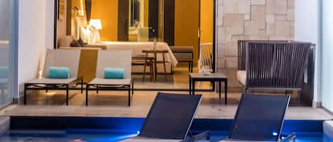 A modern indoor pool area with lounge chairs and a seating area.