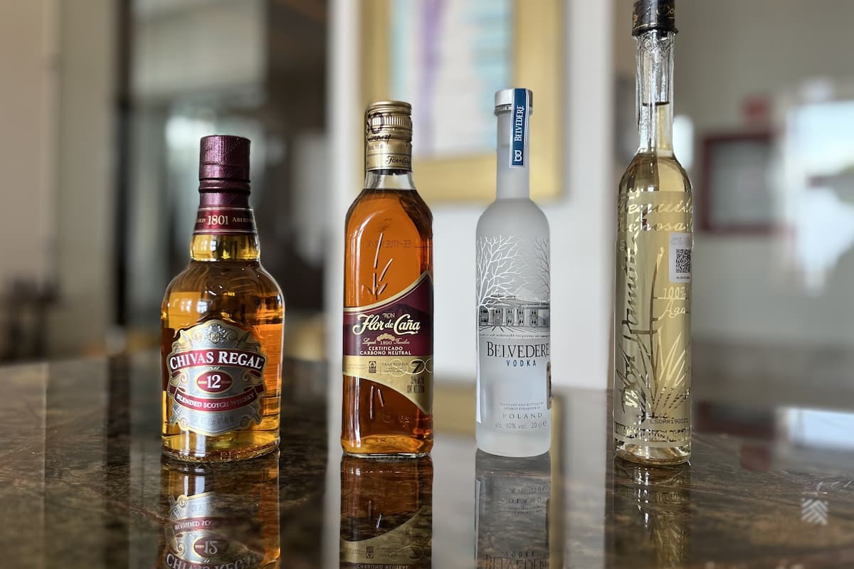 Four bottles of alcoholic beverages on a reflective surface.