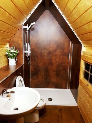 A compact bathroom with a shower, toilet, and sink. - Skye Cabins (Skeabost)