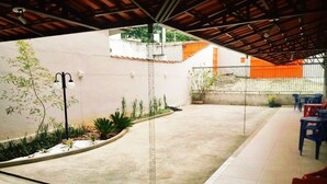 Un espacio al aire libre cubierto con piso de concreto, un farol negro y un pequeño jardín con plantas.