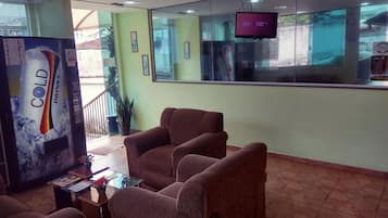 A reception area with a reception desk, a television mounted on the wall, and several brown armchairs.