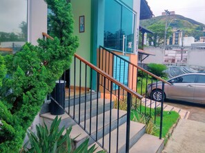 Un edificio moderno con una escalera, un automóvil estacionado y un césped verde.