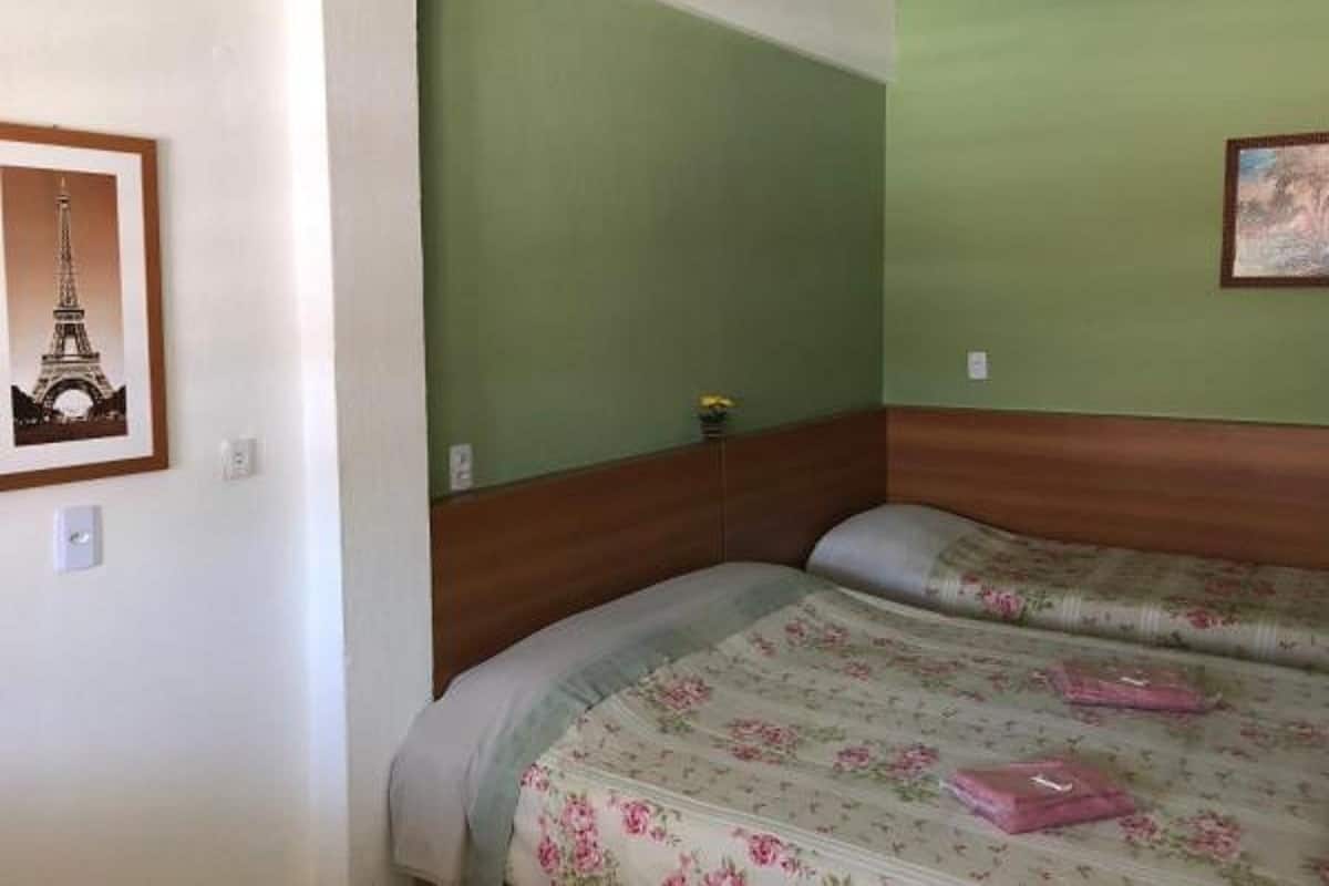 Un dormitorio con dos camas, paredes verdes y un cuadro con la Torre Eiffel.