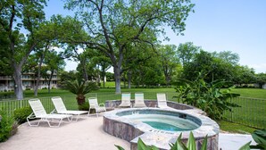 An outdoor hot tub area with lounge chairs and a stone pool. - Urban Bungalow WW C301 2 Bedroom Condo by RedAwning (New Braunfels)