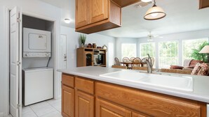 A modern kitchen with wooden cabinets, a built-in dishwasher, and a large island sink. - Urban Bungalow WW C301 2 Bedroom Condo by RedAwning (New Braunfels)