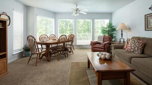 A living room with a dining table, chairs, a sofa, a coffee table, and a ceiling fan. - Urban Bungalow WW C301 2 Bedroom Condo by RedAwning (New Braunfels)