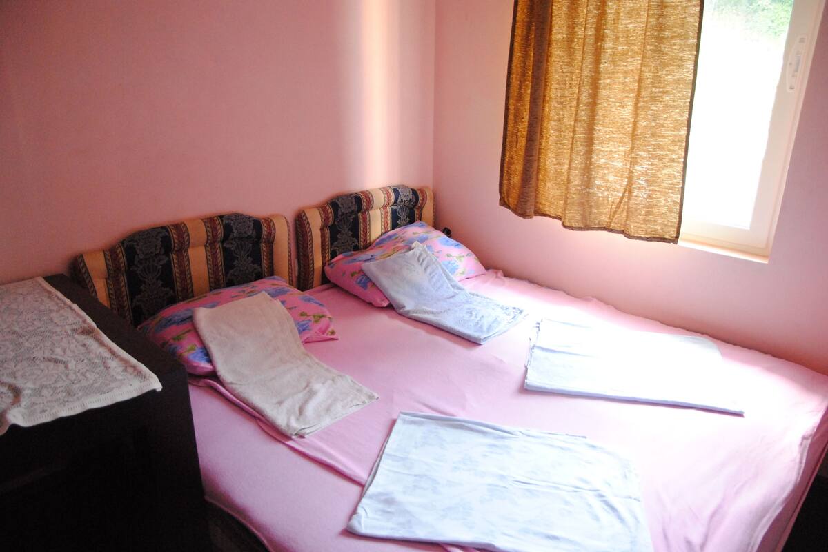 Una cama individual con una colcha rosa, dos almohadas y un cabecero con diseño estampado.