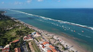A coastal town with a beach, ocean, and residential buildings. - Pousada Encantos da Natureza (Marechal Deodoro)