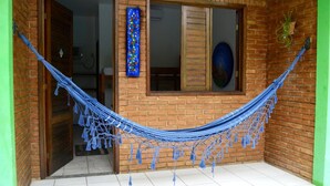 A hammock tied between two brick walls with a window and a door. - Pousada Encantos da Natureza (Marechal Deodoro)