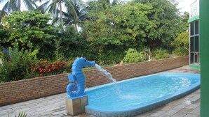A swimming pool with a blue seahorse sculpture and a brick wall. - Pousada Encantos da Natureza (Marechal Deodoro)
