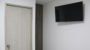 A room with a closed door, a wardrobe, and a mounted flat-screen TV on the wall. - Hotel Pereira 421 (Pereira)