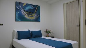 A bedroom with a bed, a nightstand, a potted plant, and a door. - Hotel Pereira 421 (Pereira)