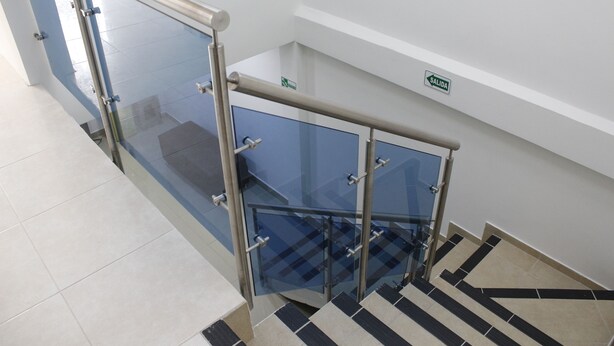 A staircase with glass railings and a sign indicating an exit. - Hotel Pereira 421 (Pereira)