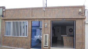 A building with two numbered doors, a visible car through the window, and a small electrical box on the wall. - Hotel Pereira 421 (Pereira)