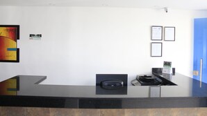 A reception desk with a black countertop, a security camera above, framed certificates on the wall, and a blue door to the right. - Hotel Pereira 421 (Pereira)