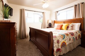 A bedroom with a wooden bed, beige curtains, a ceiling fan, and a potted plant. - River Relaxation Ww A302 2 Bedroom Condo by RedAwning (New Braunfels)