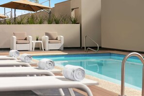 Una piscina al aire libre, sillones reclinables de piscina