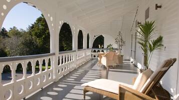 A covered outdoor area with wicker furniture, white railings, and potted plants.