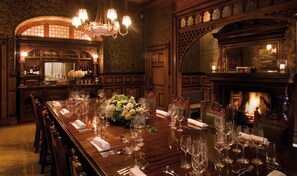 A formal dining room with a long table set for a meal, surrounded by ornate wooden furniture and a fireplace. - Otahuna Lodge (Tai Tapu)
