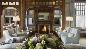 Una sala de estar acogedora con chimenea, asientos cómodos y un arreglo floral.