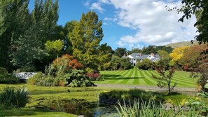 A well-maintained garden with a pond, a lawn, and a large house in the background. - Otahuna Lodge (Tai Tapu)