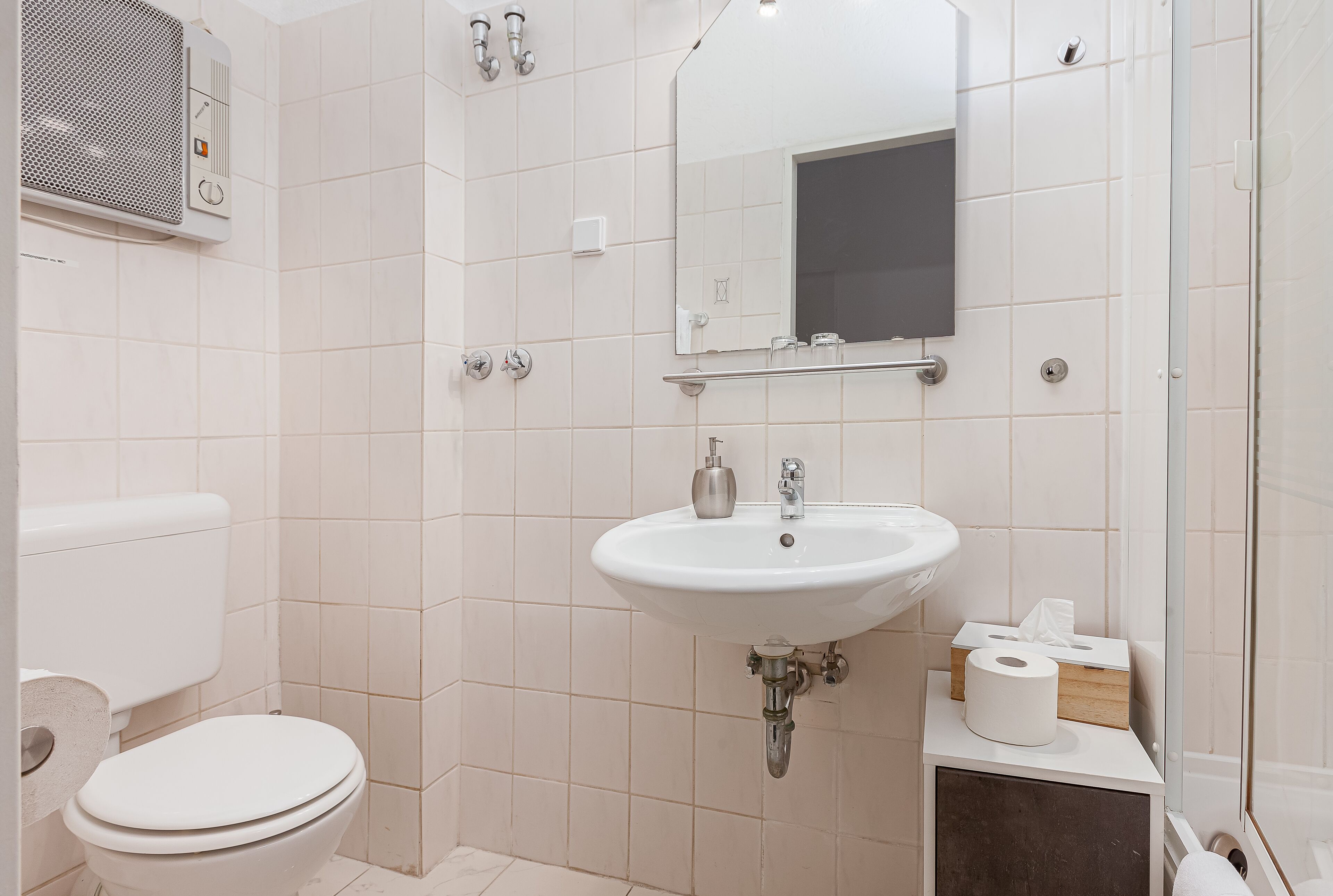 A bathroom with a toilet, sink, and shower.