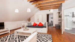 Una sala de estar moderna con un sofá, una mesa de centro y un televisor. Se ve un baño a través de una puerta abierta.