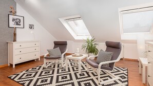 Un dormitorio estilo loft moderno con techo inclinado, tragaluces, alfombra de diseño geométrico y mobiliario minimalista.