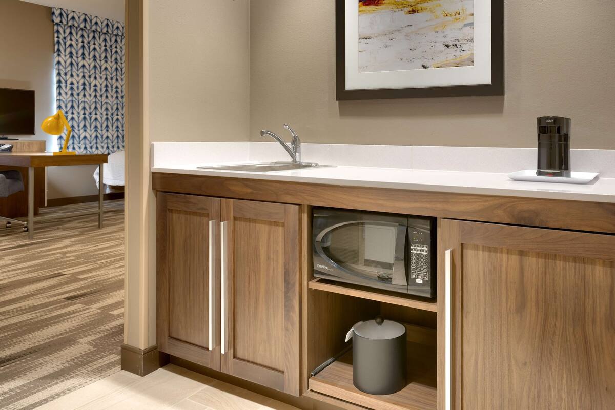 A modern kitchen with a built-in microwave, a sink, and a coffee maker on the countertop.
