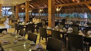Ein Restaurant mit mehreren Tischen und Stühlen, einem Buffet und Blick ins Freie.