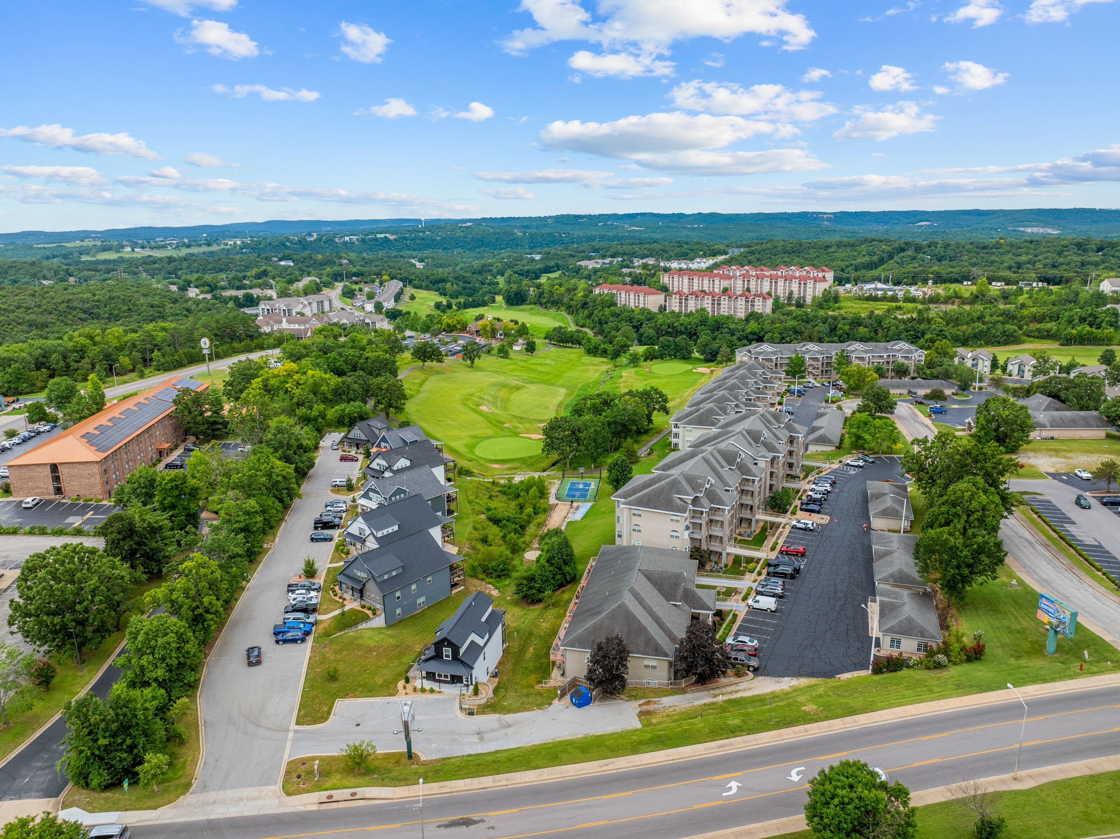 Un quartier résidentiel comprenant plusieurs immeubles d’appartements, un terrain de golf et un parking.