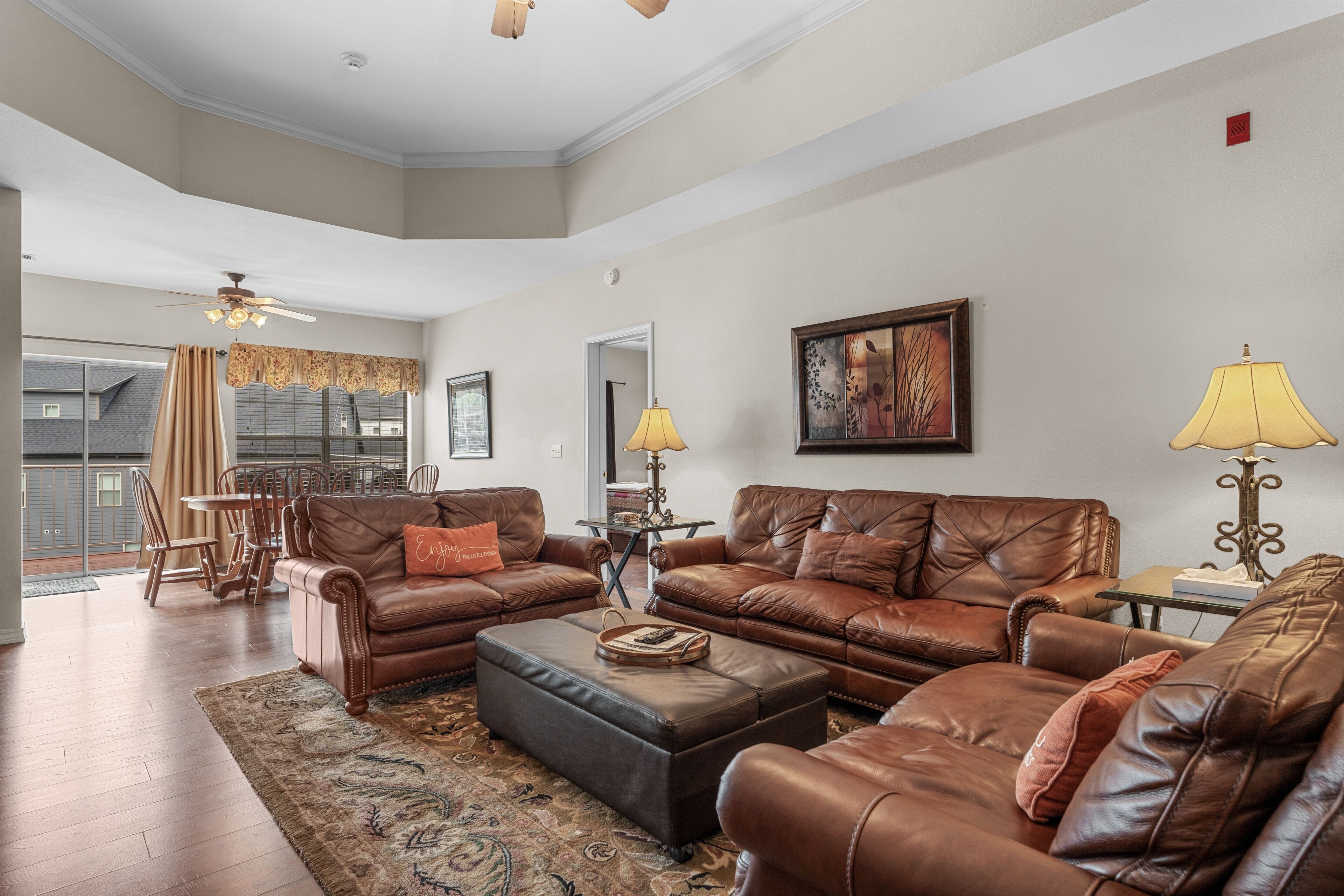 A spacious living room with leather sofas, a coffee table, and a dining area with chairs and a table.