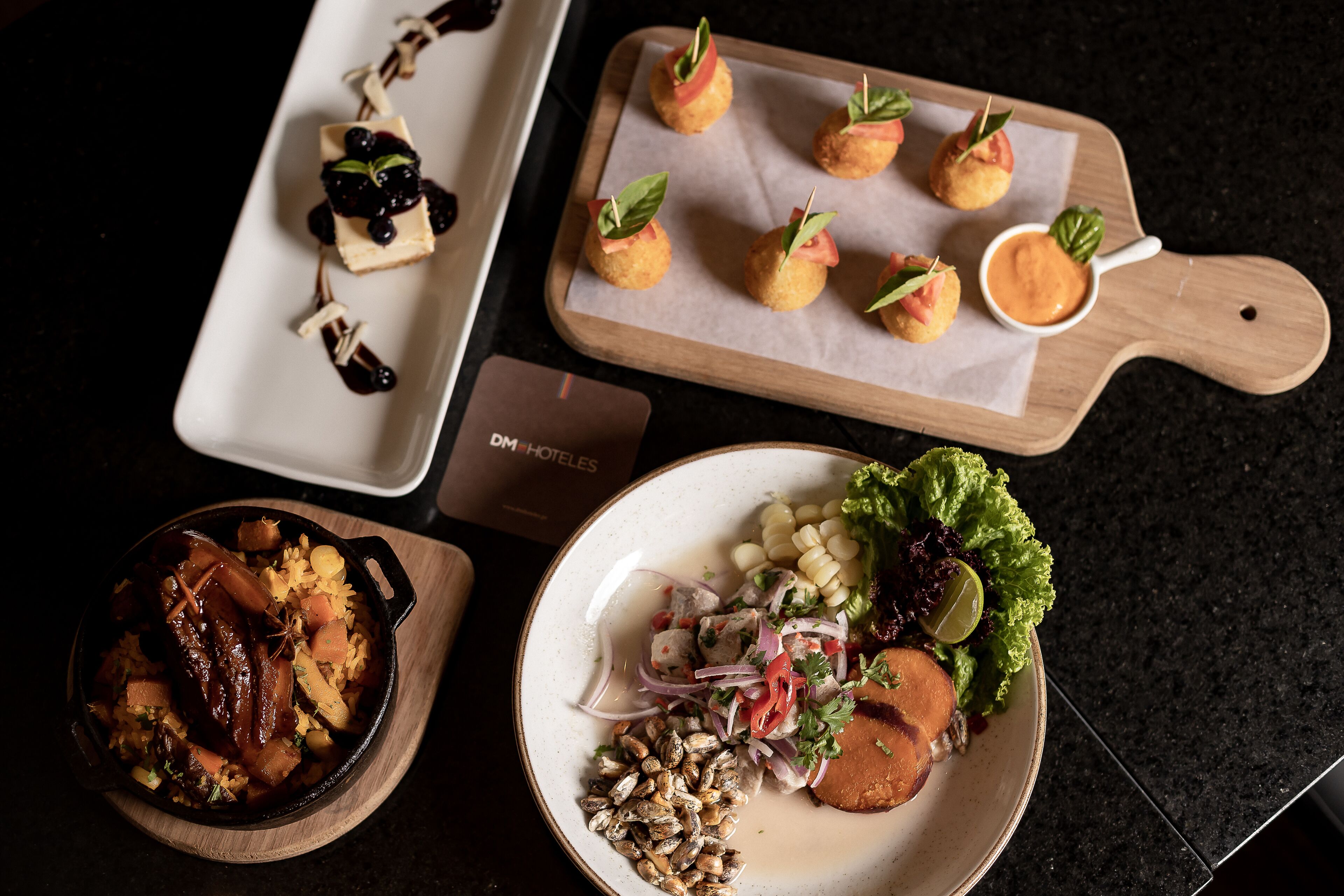 A variety of dishes on a table, including a plate with corn, lettuce, and a lime wedge, a bowl of seafood, and appetizers on a wooden board.