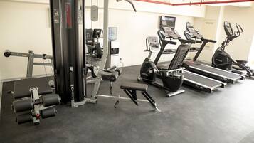 Ein Fitnessstudio mit unterschiedlicher Trainingsausstattung, darunter Laufbänder, eine Hantelbank und ein Squat-Gestell.