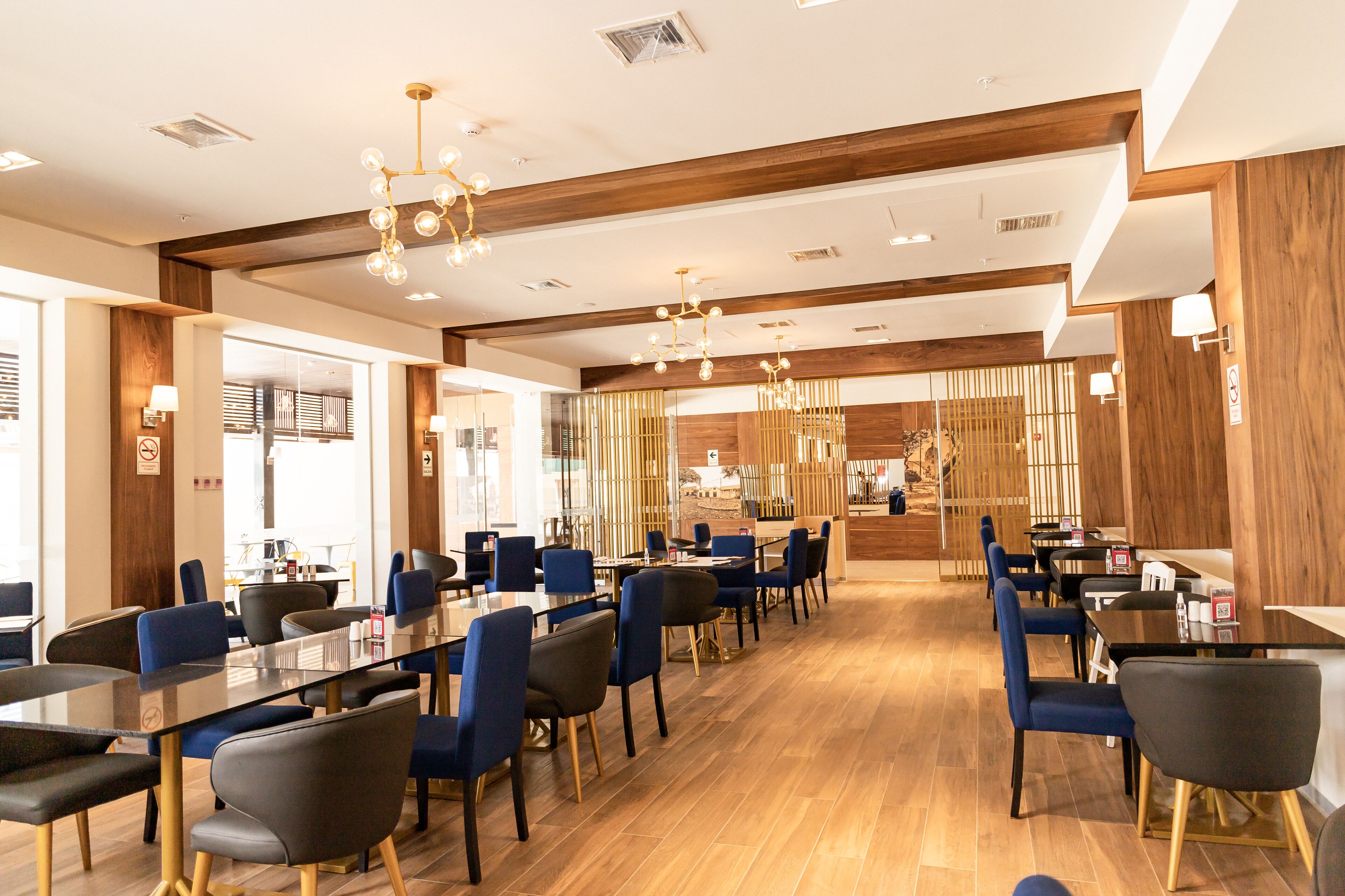 Ein modernes Restaurant mit langen Tischen, blauen Stühlen und Holzboden.