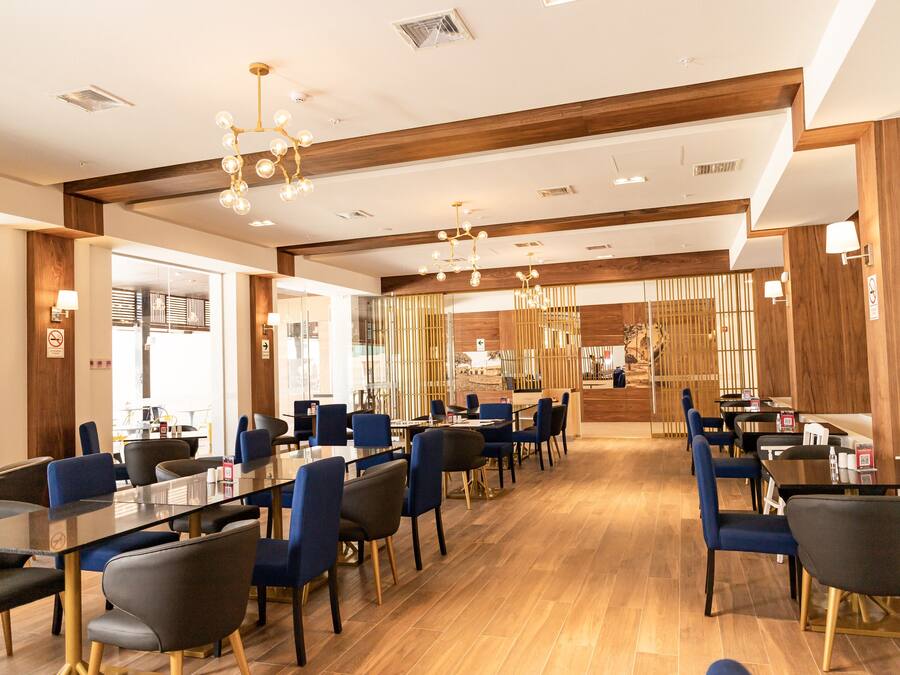 Ein modernes Restaurant mit langen Tischen, blauen Stühlen und Holzboden.