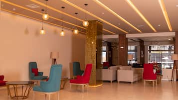 A modern lobby with seating areas, a decorative wall, and a reception desk.