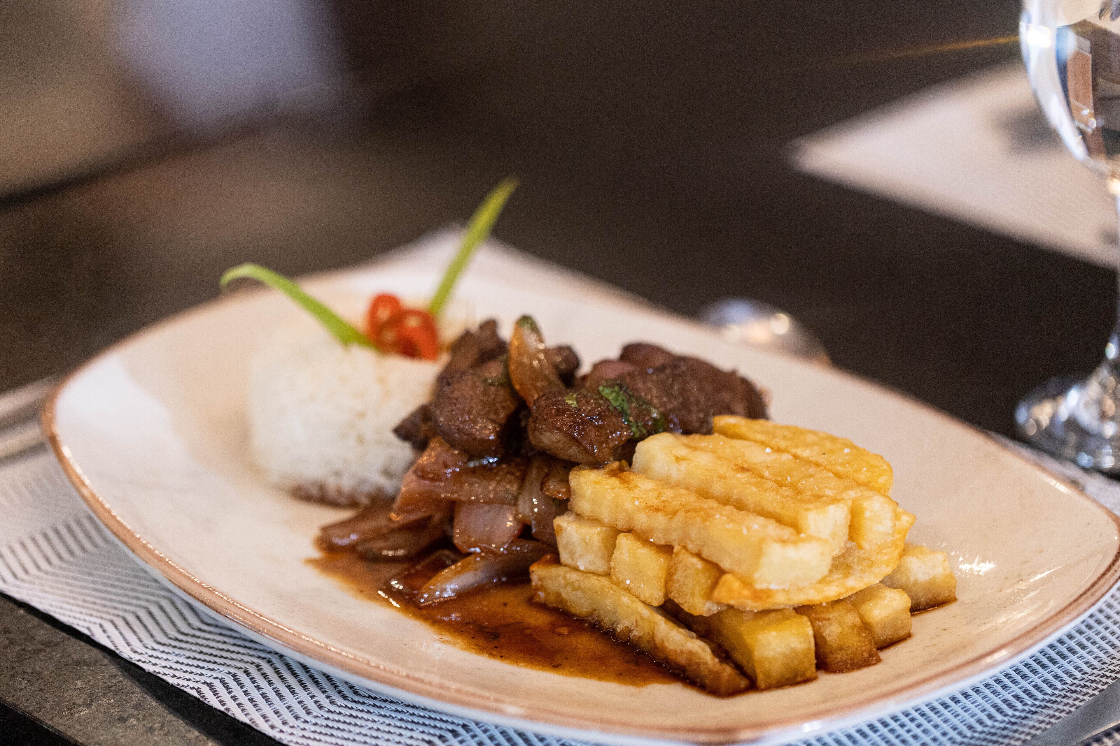 A plate with white rice, beef, and French fries.