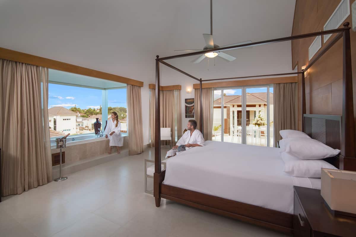 A spacious bedroom with a large bed, a ceiling fan, and a view of the outside.
