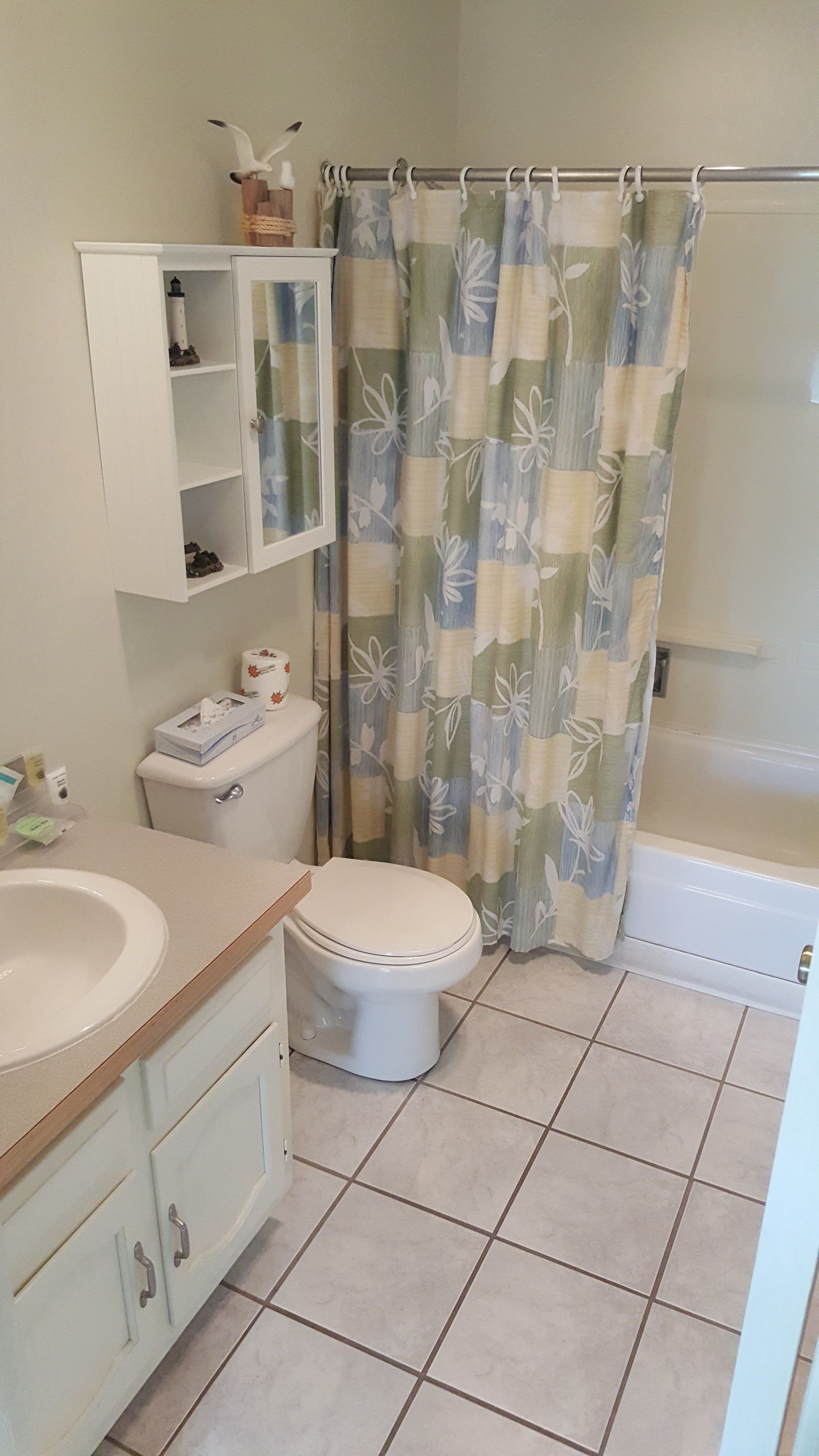 A bathroom with a toilet, sink, cabinet, and shower curtain.
