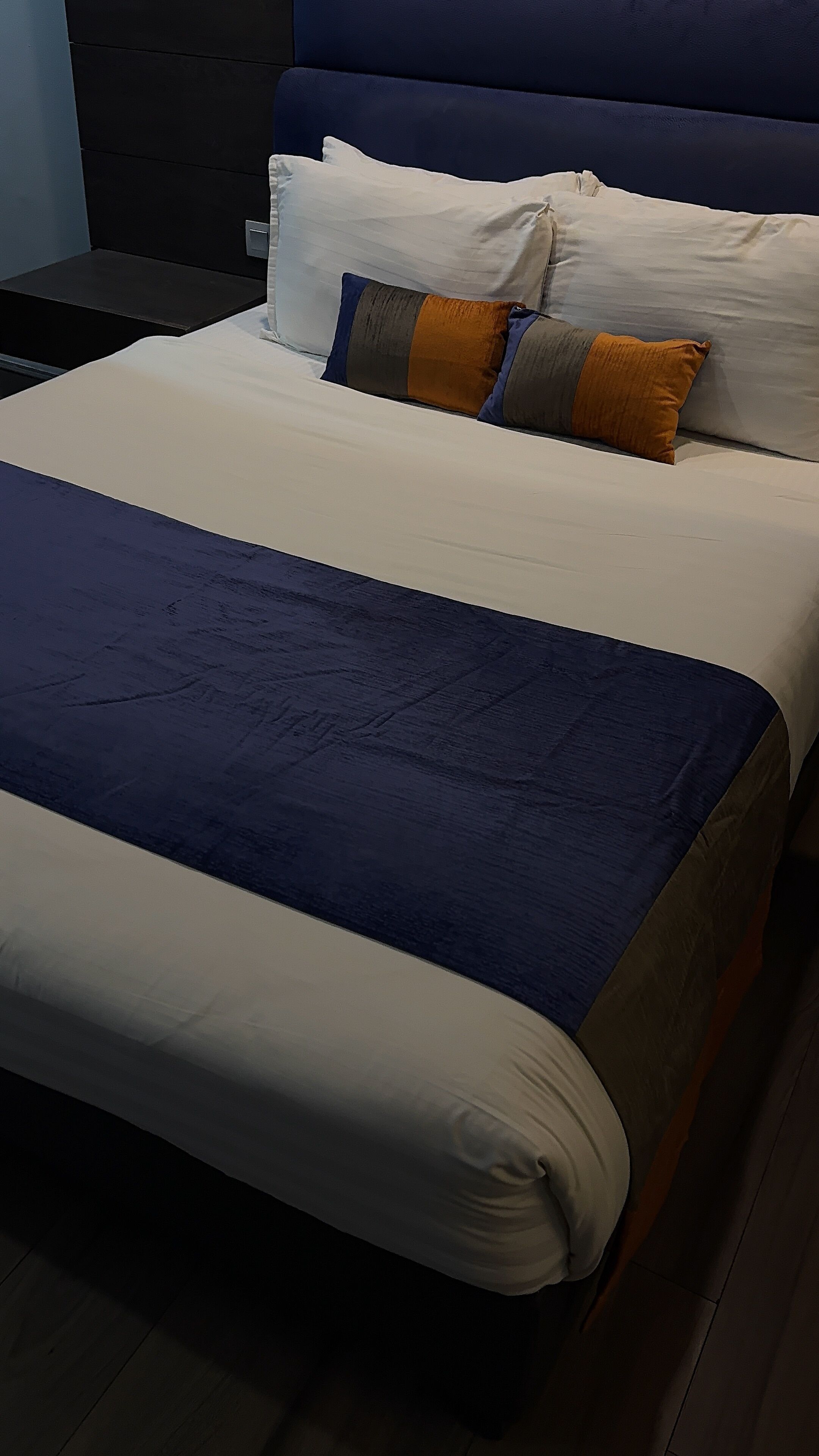 Una cama con una colcha azul y blanca, una almohada blanca y una almohada a rayas.