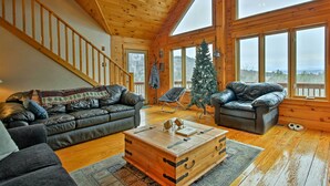 Interior acogedor de una cabaña con una escalera de madera, sofás de cuero, una mesa de centro de madera y un árbol de Navidad.