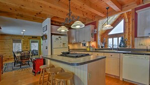 Una cocina acogedora de estilo rústico con vigas de madera, una isla central con taburetes y un refrigerador.