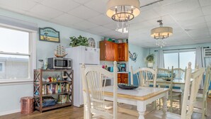 A dining area with a white table and chairs, a bookshelf, a microwave, and a refrigerator. - Oceanfront condos with 3 night minimum rentals and linens included! (Ocean City)