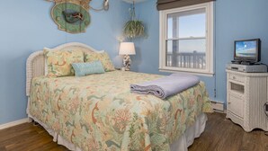 A bedroom with a bed, a television, a window with a view, and a wall clock. - Oceanfront condos with 3 night minimum rentals and linens included! (Ocean City)