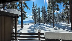 Une forêt enneigée avec un chalet en bois et une vue sur des montagnes au loin.