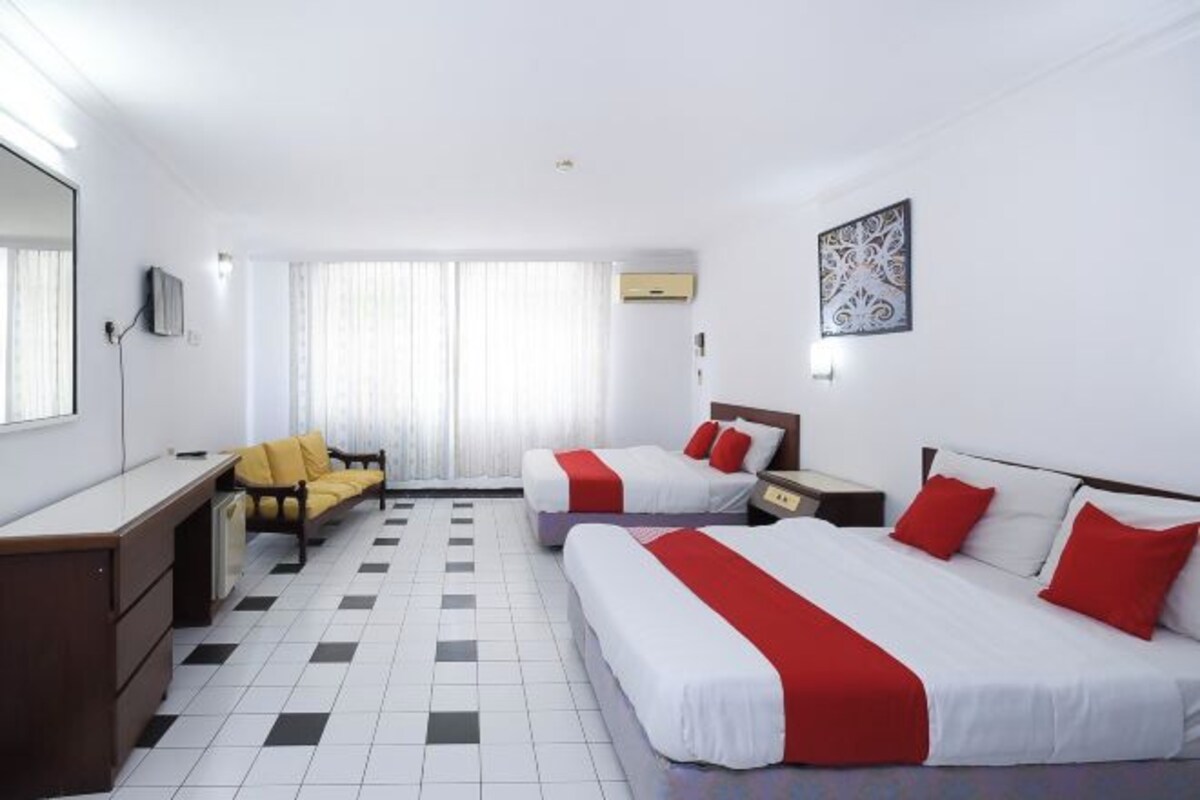 Une chambre d’hôtel avec deux lits, un bureau, une chaise et une grande fenêtre avec des rideaux.