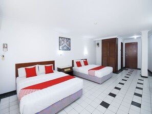 Een hotelkamer met twee bedden, witte wanden, een vloer met patroon en een houten deur.