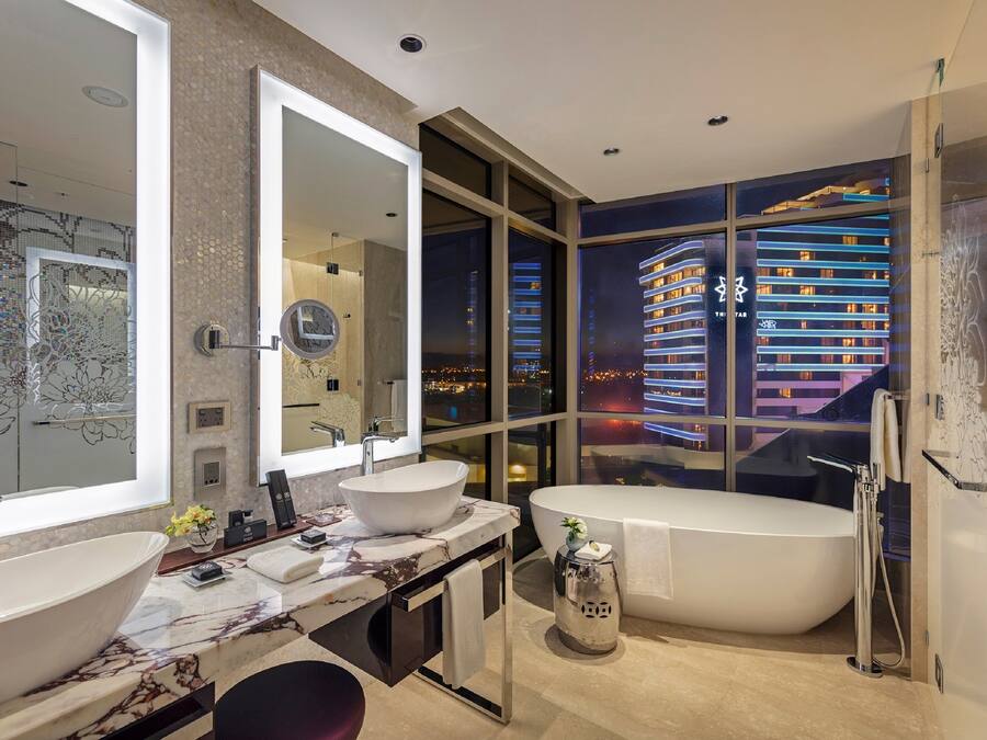 A modern bathroom with two sinks, a large mirror, and a bathtub.