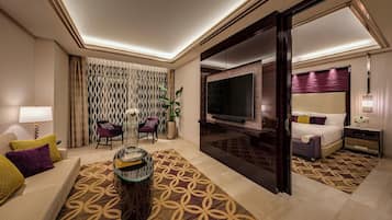 A hotel room with a sofa, a coffee table, a TV, a bed, and a sliding door.